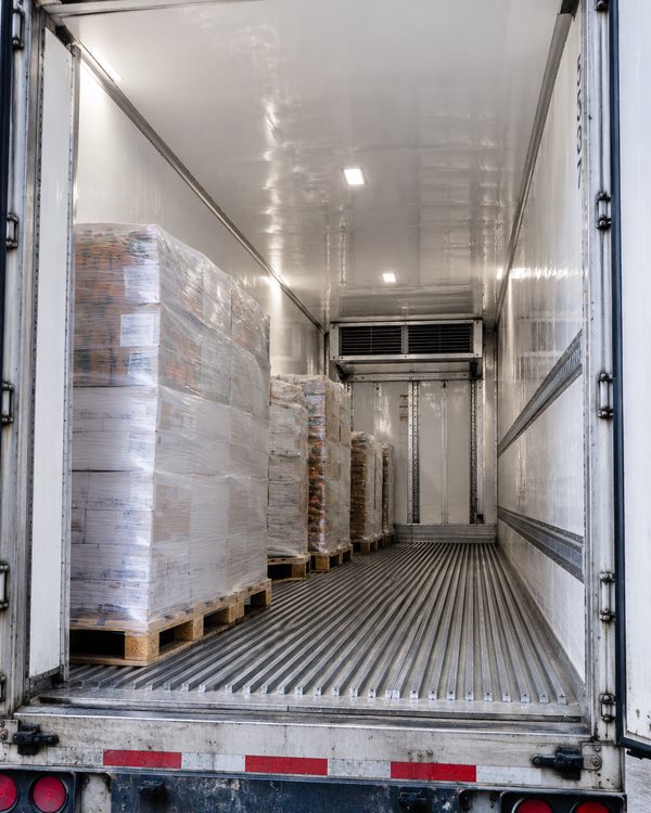 Inside a refrigerated trailer at a dock, pallets loaded, evaporator unit and duct floor visible.